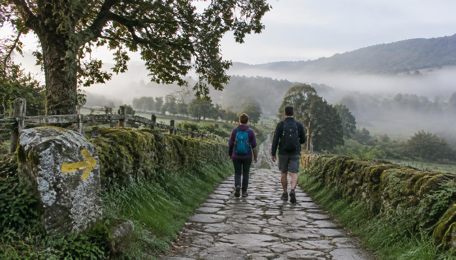 Walkers on a granite lane through Galician countryside